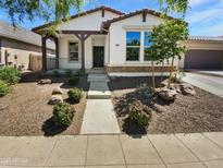 Charming single-story home with manicured desert landscaping and a covered front porch at 15369 W Wethersfield Rd, Surprise, AZ 85379