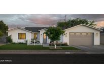 Charming exterior showcases a well-maintained lawn and a gray two-car garage with beautiful landscaping at 3101 E Sells Dr, Phoenix, AZ 85016
