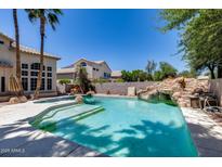 Backyard pool with a rock waterfall feature and mature landscaping, perfect for outdoor relaxation at 7217 S Hazelton Ln, Tempe, AZ 85283