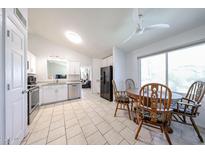 Eat-in kitchen features white cabinets, stainless steel appliances, tile floors, and a four-chair dining table at 8521 W Mauna Loa Ln, Peoria, AZ 85381
