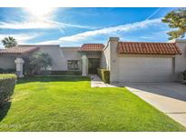 Charming single-story home featuring a terra cotta tile roof, lush green lawn, and a private two-car garage at 9463 E Jenan Dr, Scottsdale, AZ 85260