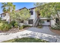 Condo exterior with red tile roof, mature landscaping, covered stairs, and light-colored walls at 9990 N Scottsdale Rd # 2042, Paradise Valley, AZ 85253