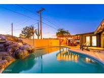 Inviting backyard pool with rock waterfall feature, pergola, and manicured landscaping creates a serene outdoor oasis at 10240 N 34Th Pl, Phoenix, AZ 85028
