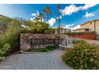 Stone sign for Four Peaks Condominium Homes with plants, blue sky, palm trees, and fountains create an inviting entrance at 13700 N Fountain Hills Blvd # 155, Fountain Hills, AZ 85268
