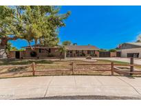 Charming single-story home with a brick facade, mature landscaping, and a decorative wooden fence in front at 1817 W Seldon Ln, Phoenix, AZ 85021