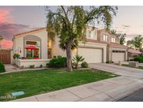 Charming two-story home with a three car garage, lush landscaping, and a lovely red umbrella on the front patio at 213 E Vaughn Ave, Gilbert, AZ 85234