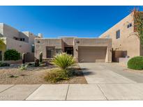 A tan home with xeriscaping and native plants, a stone facade, and an attached two-car garage at 10869 E Hedgehog Pl, Scottsdale, AZ 85262