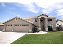 Charming two-story home featuring a well-manicured lawn, tan stucco, and three-car garage at 1374 N Alexis Dr, Gilbert, AZ 85234