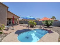 Backyard features a relaxing pool area with gravel landscaping, brick patio, and shade umbrellas at 1813 N Lewis Pl, Casa Grande, AZ 85122