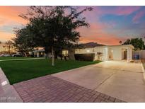 Charming single-story home featuring a well-manicured lawn, mature trees, and a long driveway leading to a covered parking area at 728 E State Ave, Phoenix, AZ 85020