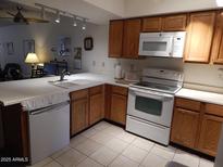 A well-maintained kitchen featuring white appliances, ample counter space, and wooden cabinetry at 8651 E Royal Palm Rd # 118, Scottsdale, AZ 85258