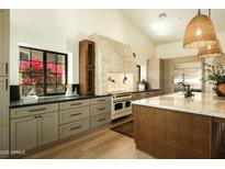 Bright kitchen featuring stone accents, wood floors, and high-end appliances under a vaulted ceiling at 8910 E Topeka Dr, Scottsdale, AZ 85255