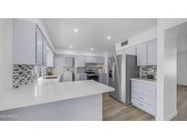 Renovated kitchen with stainless steel fridge, modern gray cabinetry, and sleek quartz countertops at 9911 W Pleasant Valley Rd, Sun City, AZ 85351