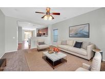 Bright living room featuring neutral walls, plush seating, ceiling fan, and seamless flow into the kitchen space at 6330 W Constance Way, Laveen, AZ 85339
