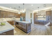 Modern kitchen features custom cabinets, a center island, stainless appliances and stone backsplash at 7438 E Visao Dr, Scottsdale, AZ 85266