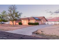 Spacious single-story home featuring an extended driveway, solar panels and a charming white fence at 23717 N Mustang Way, Florence, AZ 85132