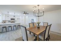 Open-concept dining area with a modern chandelier and adjacent kitchen island for seamless entertaining at 3722 W Michelle Dr, Glendale, AZ 85308
