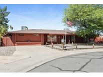 Charming single-story home with an American flag, desert landscaping, and a red brick exterior at 3836 W Desert Cove Ave, Phoenix, AZ 85029