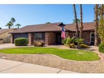 Charming single-story brick home with well-maintained landscaping and an American flag at 4418 E Paradise Ln, Phoenix, AZ 85032