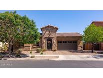 This single-Gathering home has stone accents, a tile roof, mature landscaping, and a wrought iron gate at the front entry at 10402 E Starion Ave, Mesa, AZ 85212