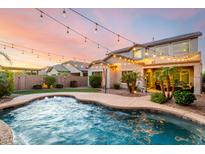 Inviting backyard pool area with string lights, tropical landscaping, and a covered patio perfect for outdoor entertaining at 11127 E Tripoli Ave, Mesa, AZ 85212