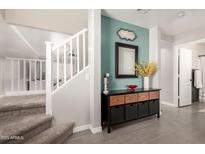 Inviting entryway featuring stairs, tiled floor, and stylish console table with a mirror at 11473 W Austin Thomas Dr, Surprise, AZ 85378