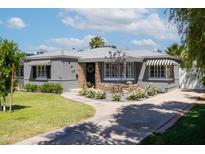 Charming home showcasing a landscaped front yard, stone accents, and black and white striped awnings at 338 W Encanto Blvd, Phoenix, AZ 85003