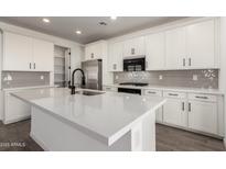 Modern kitchen featuring white cabinets, stainless steel appliances, and a large center island with a white countertop at 4034 W Nora Dr, San Tan Valley, AZ 85144