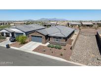 Front exterior featuring desert landscaping, a blue-gray garage door, a stone accent wall, and mountain views at 41800 W Sonoran Trl, Maricopa, AZ 85138