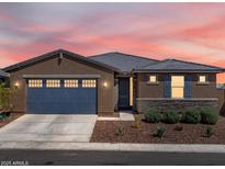 Charming single-story home with a blue garage door, stone accents, and desert landscaping at sunset at 41800 W Sonoran Trl, Maricopa, AZ 85138