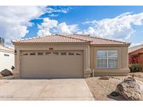 Charming home featuring a tile roof, tan stucco, a 2-car garage, and desert landscaping for low maintenance appeal at 4387 E Hartford Ave, Phoenix, AZ 85032
