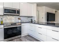 Bright kitchen features stainless steel appliances, dark counters, white cabinets and sleek design at 9013 E Shooting Star Dr, Gold Canyon, AZ 85118
