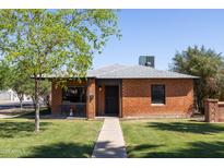 Charming brick home with a well-manicured lawn, mature tree, and inviting front porch at 1546 W Culver St, Phoenix, AZ 85007