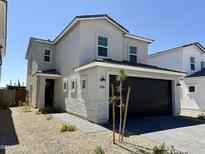 Charming two-story home featuring neutral stucco, stone accents, a black garage door, and desert landscaping at 1564 N Pueblo Dr, Apache Junction, AZ 85120