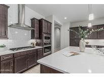 Gourmet kitchen featuring a gas cooktop, subway tile backsplash, and stainless steel hood at 18025 N 65Th Pl, Phoenix, AZ 85054