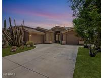 Charming single-story home with desert landscaping, large driveway, and two-car garage at dusk at 4667 E County Down Dr, Chandler, AZ 85249
