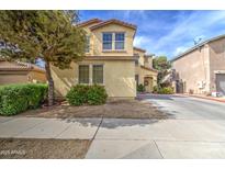 Two-story home with a stucco exterior, landscaping, and a tree in the front yard on a sunny day at 17374 W Adams St, Goodyear, AZ 85338