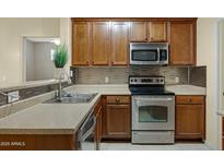 Well-lit kitchen featuring stainless steel appliances, tile backsplash, and wooden cabinetry at 3330 S Gilbert Rd # 1020, Chandler, AZ 85286