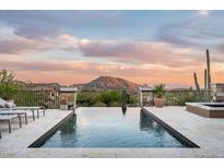 Inviting infinity pool and spa offer stunning mountain views at sunset, perfect for relaxing or entertaining at 42155 N 97Th Way, Scottsdale, AZ 85262