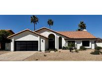 Charming single-story home with a desert landscape, black garage door and a terracotta tile roof at 5402 E Michelle Dr, Scottsdale, AZ 85254