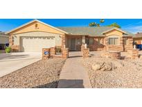 Charming single-story home with a stone accent facade, a two car garage and a well manicured desert landscape at 7002 E Exmoor Dr, Mesa, AZ 85208