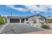 Charming single-story home with a spacious driveway, desert landscaping, and a modern garage door at 8316 E Glenrosa Ave, Scottsdale, AZ 85251