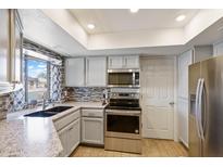 Bright kitchen features stainless steel appliances, stylish backsplash, and granite countertops at 905 E Bluefield Ave, Phoenix, AZ 85022