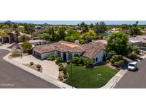Expansive desert home featuring a tile roof, lush landscaping, circular driveway, and multi-car garage at 10205 E Corrine Dr, Scottsdale, AZ 85260