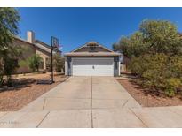 Charming home with a gray exterior, a two-car garage, and a basketball hoop in the driveway at 6320 W Mercer Ln, Glendale, AZ 85304