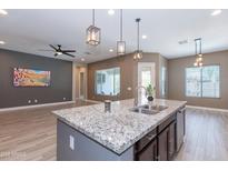 Stylish kitchen with granite countertops, pendant lights, and an island with a stainless steel sink at 20084 E Rosa Rd, Queen Creek, AZ 85142
