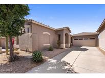 Tan home exterior with tile roof, desert landscaping, and a spacious driveway leading to the attached garage at 2610 W Sat Nam Way, Phoenix, AZ 85086