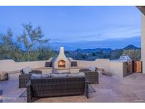 Outdoor patio featuring cozy seating, a fireplace, built-in grill and stunning mountain views at 28437 N 112Th Way, Scottsdale, AZ 85262