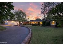 Charming single-story home with lush lawn, brick accents, and attached garage under a captivating sunset at 5818 N 3Rd Ave, Phoenix, AZ 85013