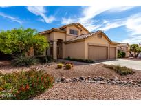 Inviting home featuring desert landscaping with vibrant plants and a three-car garage at 7261 E June St, Mesa, AZ 85207